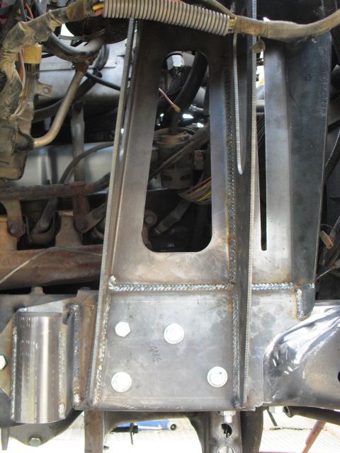 1986 Ford Bronco - Close-up view of custom-fabricated coilover shock tower components, showing welding and bolt attachments.