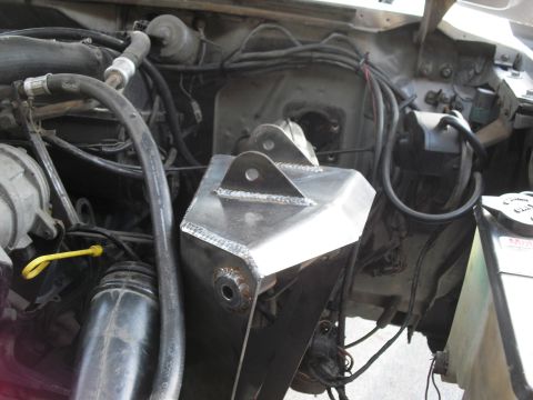 1986 Ford Bronco - Close-up of a custom-fabricated metal mount in the engine compartment, likely for suspension modification.