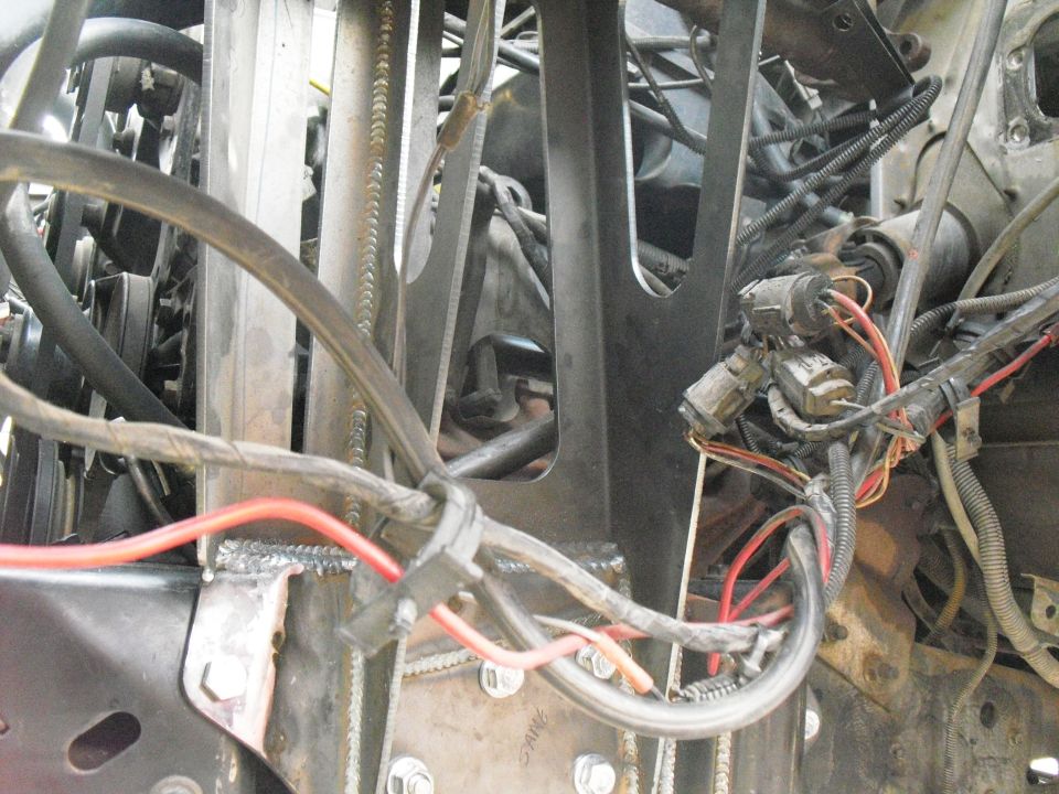 Engine bay with tangled wires, metal brackets, and connectors