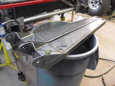 1986 Ford Bronco - Custom fabricated radius arms are shown resting on a trash can, with parts of a vehicle visible in the background.