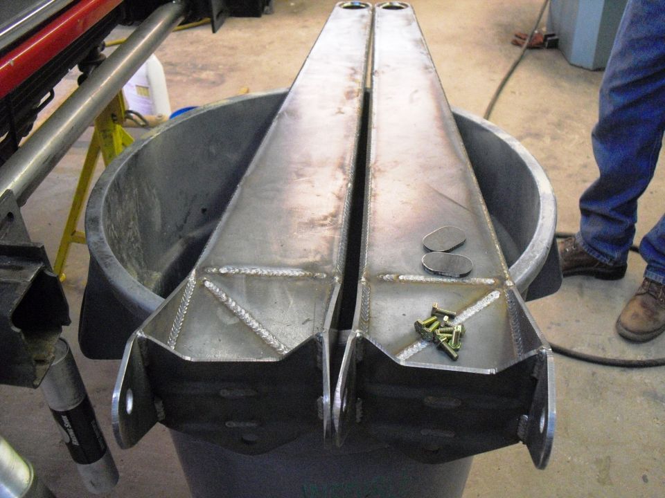 Two fabricated radius arms with hardware, resting in a tub