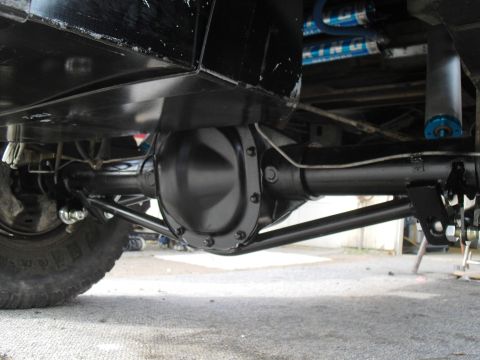 1986 Ford Bronco - Close-up of the rear axle assembly and suspension components, including a large differential housing and shock absorbers.
