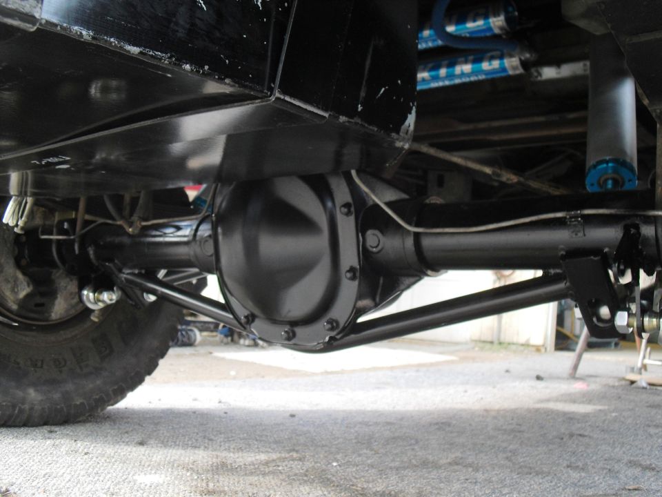 Underside view of a vehicle's rear axle, differential, and suspension with blue King shocks visible