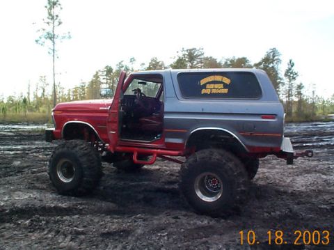 1995 Ford Bronco - This modified Ford Bronco is shown off-road in a muddy environment with its driver's door ajar.