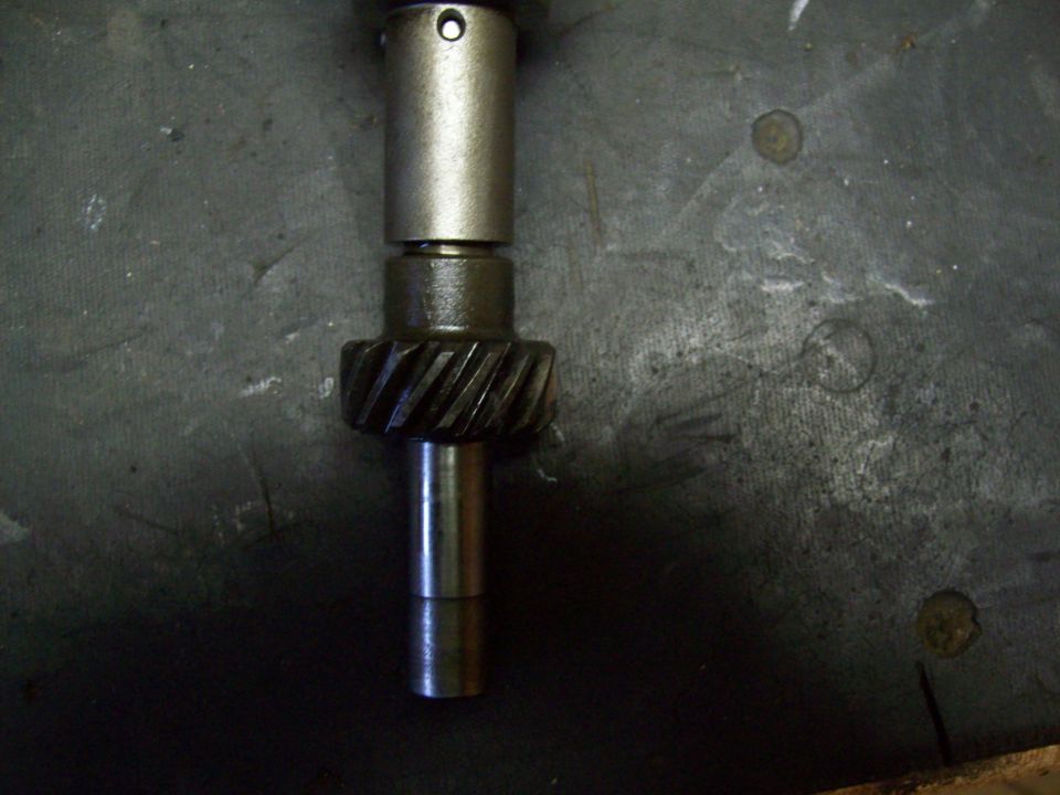 Helical gear on a stepped steel shaft resting on concrete