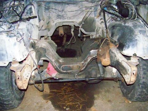 1985 Ford Bronco - The front frame and suspension of a vehicle are visible, with the engine bay appearing to be removed or heavily modified.