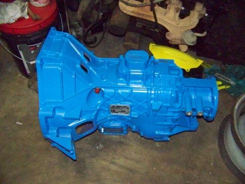 1985 Ford Bronco - A blue transmission is shown on a workshop floor, with a metal plate visible on its side.
