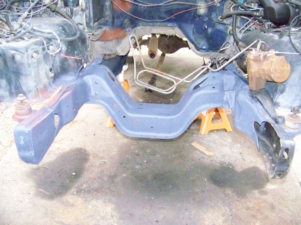 Vehicle frame with engine components and suspension parts visible, supported by jack stands