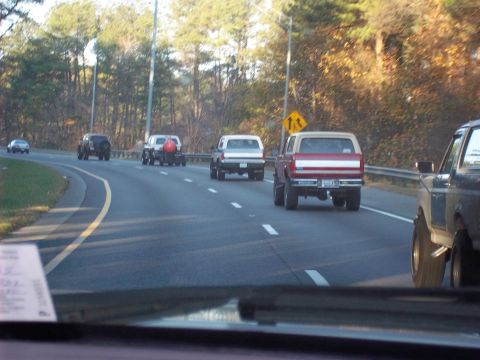 1979 Ford Bronco - A red and tan 1979 Ford Bronco is seen driving on a highway alongside other vehicles.