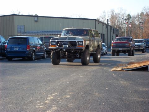 1979 Ford Bronco - Modified Ford Bronco with camouflage paint and large tires is parked in a lot.