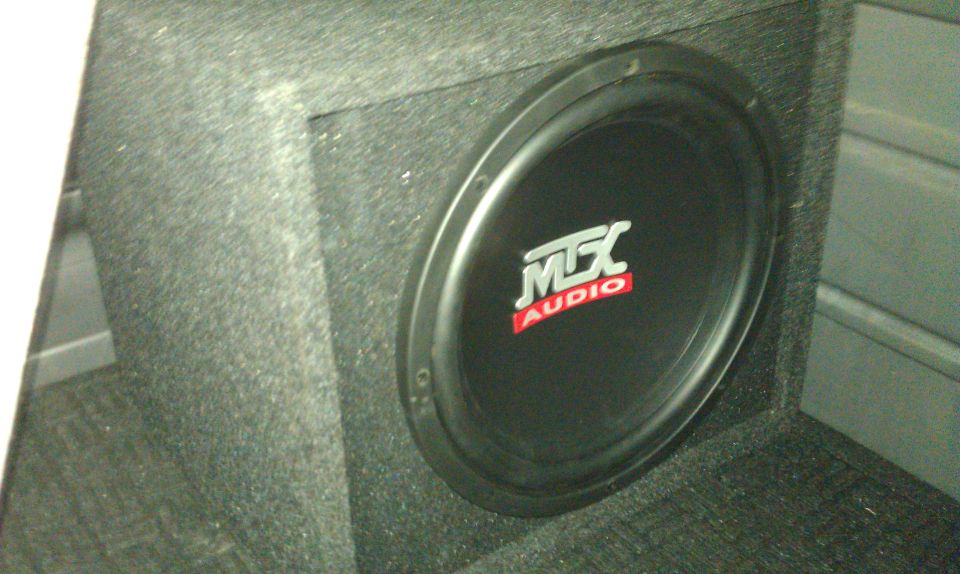 MTX Audio subwoofer in a black carpeted box installed in a vehicle interior