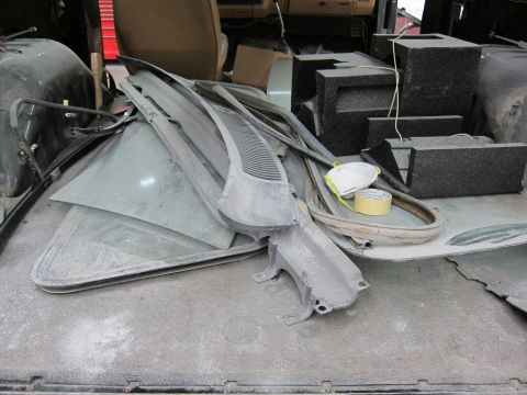 1987 Dodge 1500 - Various automotive parts are piled up, covered in dust, obscuring any specific vehicle identification.