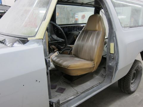 1987 Dodge 1500 - Interior view of a 1987 Dodge 1500 pickup truck, showing the tan bucket seat and dashboard during bodywork.