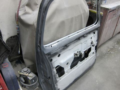 1987 Dodge 1500 - The interior of a car door, stripped down to its metal frame and window mechanisms, is visible.