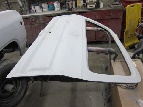 1987 Dodge 1500 - A car door is prepped for paint in a workshop environment.