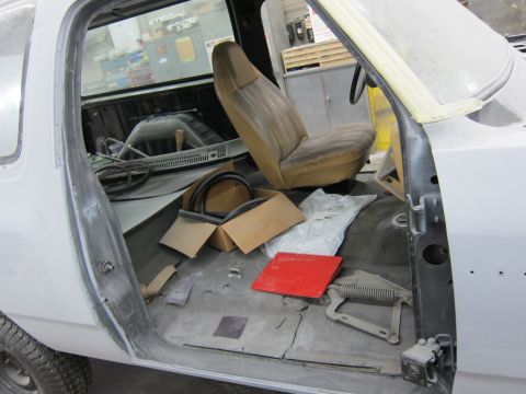 1987 Dodge 1500 - Interior view of a pickup truck undergoing repairs, with parts and supplies scattered on the floor.