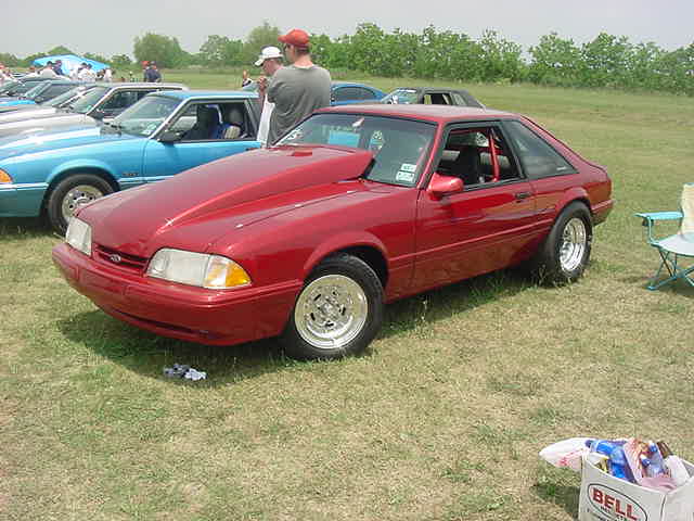 Red coupe with a large hood scoop, seen from a 3/4 front angle