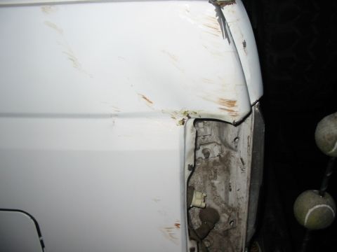 1992 Ford Bronco - Damage to the rear corner of a white vehicle, revealing exposed metal and wiring.