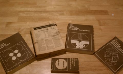 1979 Ford Bronco - A collection of service manuals and an identification guide for 1978 trucks are laid out on a wooden table.