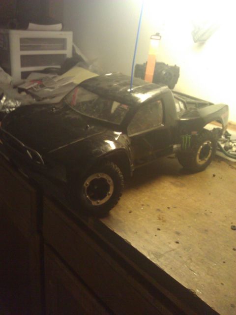 1994 Ford Bronco - A black remote control truck sits on a wooden surface, with a blue antenna extending from the roof.