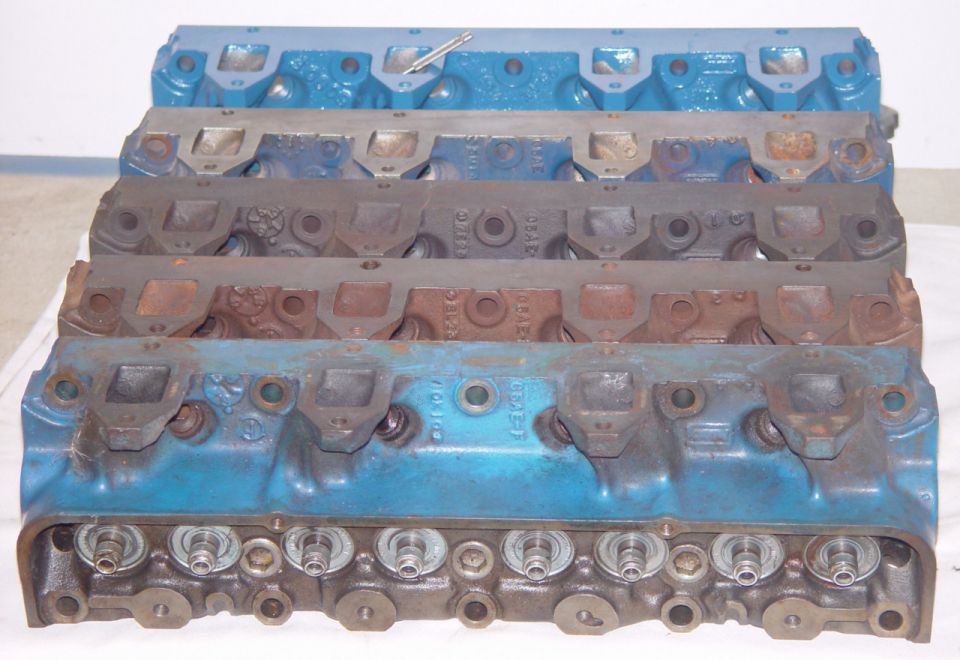 Stack of cast-iron cylinder heads, some painted blue, others bare metal.