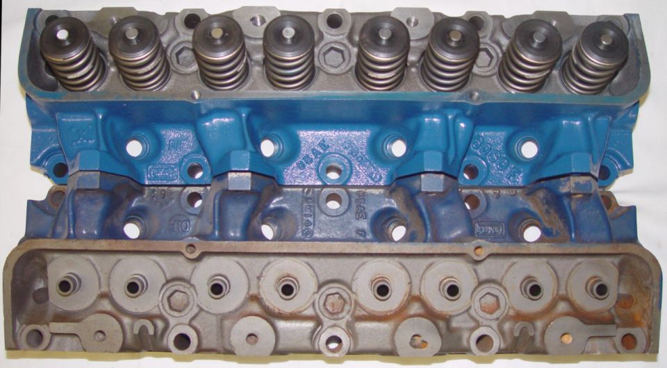 Two cast-iron cylinder heads, one with valve springs, both with blue-painted faces