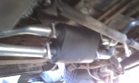 1979 Ford Bronco - The underside of a vehicle shows its exhaust system components, including the muffler and pipes.