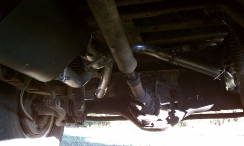1979 Ford Bronco - The underside of a vehicle reveals its exhaust pipes and rear differential.