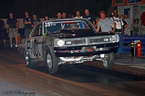 1992 Ford Mustang - A drag car launches off the line with its front wheels in the air during a race.