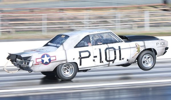 White drag car with black hood and P-101 markings, in motion on a track