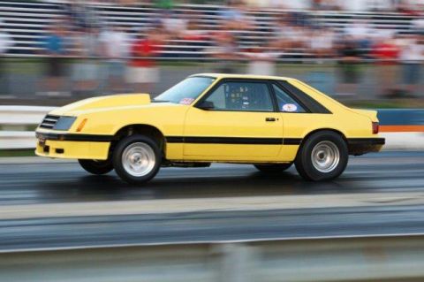 1992 Ford Mustang - A yellow 1987 Ford Mustang is captured in motion on a drag strip, its racing modifications.