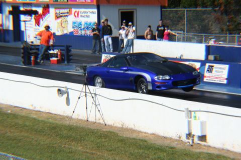1992 Ford Mustang - A blue sports car with a black hood and silver stripe races down a track.