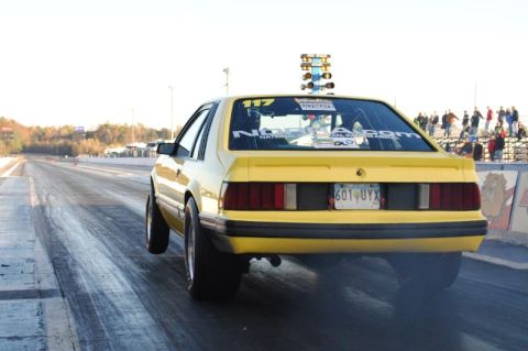 1992 Ford Mustang - Yellow 1992 Ford Mustang drag car performing a burnout on the starting line of a drag strip.