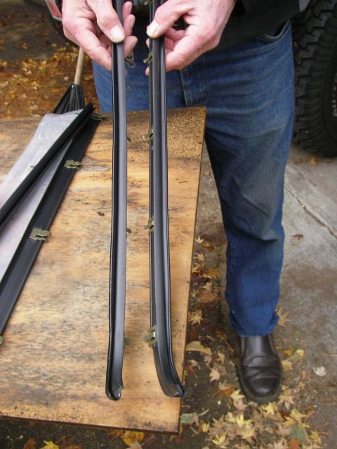 1990 Ford Bronco - Two black rubber weatherstripping pieces with metal clips are held up for inspection.