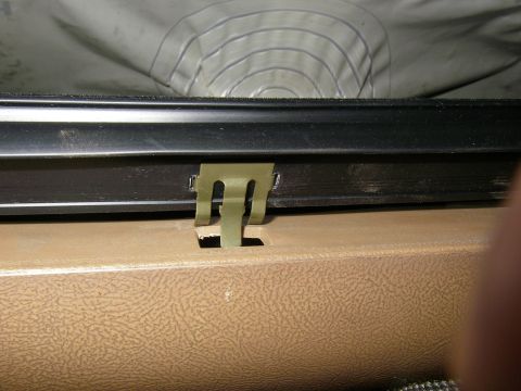 1990 Ford Bronco - Close-up of a vehicle's interior trim and a clip, likely part of the weatherstripping system.