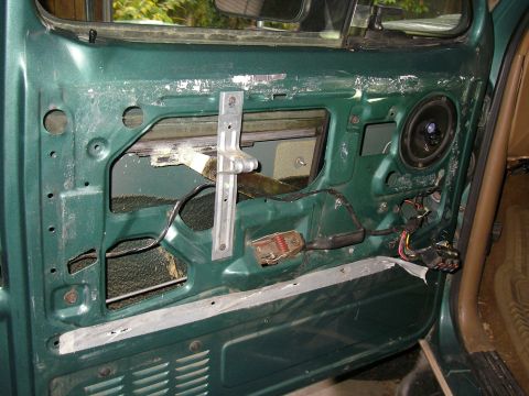 1990 Ford Bronco - Interior view of a green vehicle door with the window mechanism and speaker exposed.