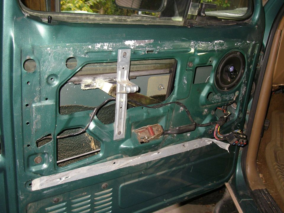 Green vehicle door interior showing window mechanism and speaker