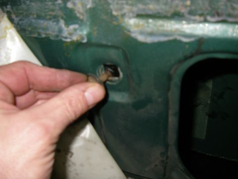 1990 Ford Bronco - A hand is shown removing a clip from the door frame of a green vehicle, revealing rust and damage.