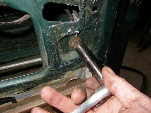 1990 Ford Bronco - Socket wrench is used to remove a bolt during weatherstripping repair on a green vehicle's door frame.