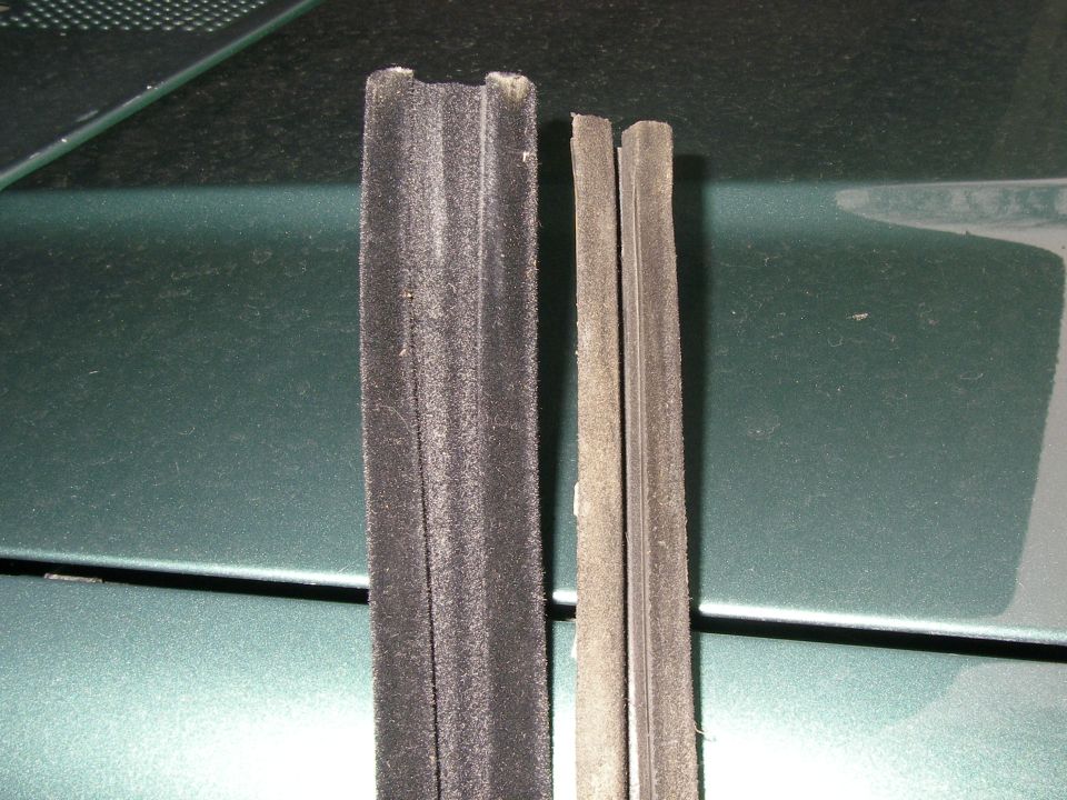 Two pieces of black weatherstripping, one thicker than the other, laid on a dark green surface