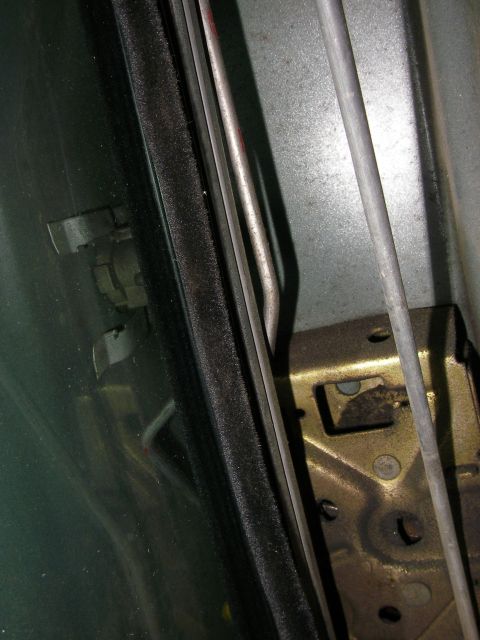 1990 Ford Bronco - Detail of a car's door latch mechanism and window weatherstripping.