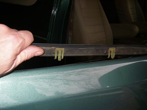 1990 Ford Bronco - A hand holds a section of door weatherstripping with yellow clips attached.
