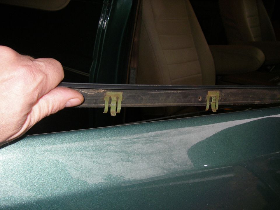 Door weatherstripping with yellow clips being held by a hand