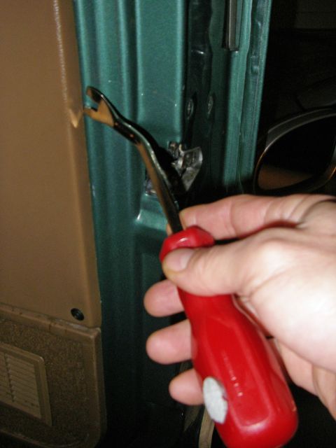 1990 Ford Bronco - A tool is used to pry off a car's interior door panel.