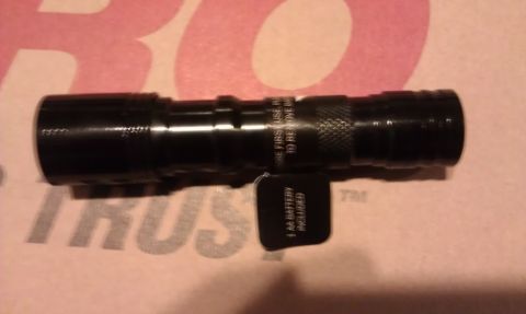 1984 Ford Bronco - Black flashlight with text on barrel and a tag indicating battery inclusion.