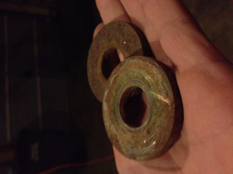 1995 Ford Bronco - A hand holds two circular, rusty metal parts with holes in the center.