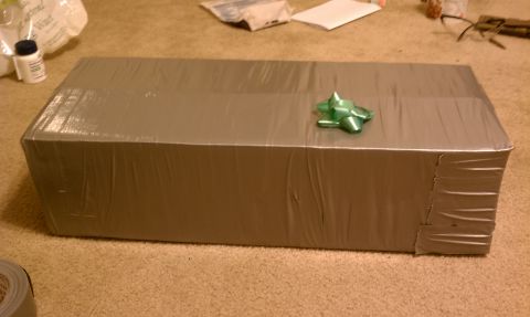 1989 Ford Bronco - A large box wrapped in gray tape sits on a carpeted floor, adorned with a green bow.