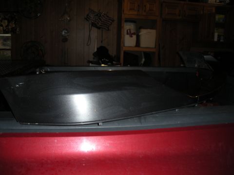 2005 Ford F-250 - A black tonneau cover is shown resting on the bed of a red pickup truck.