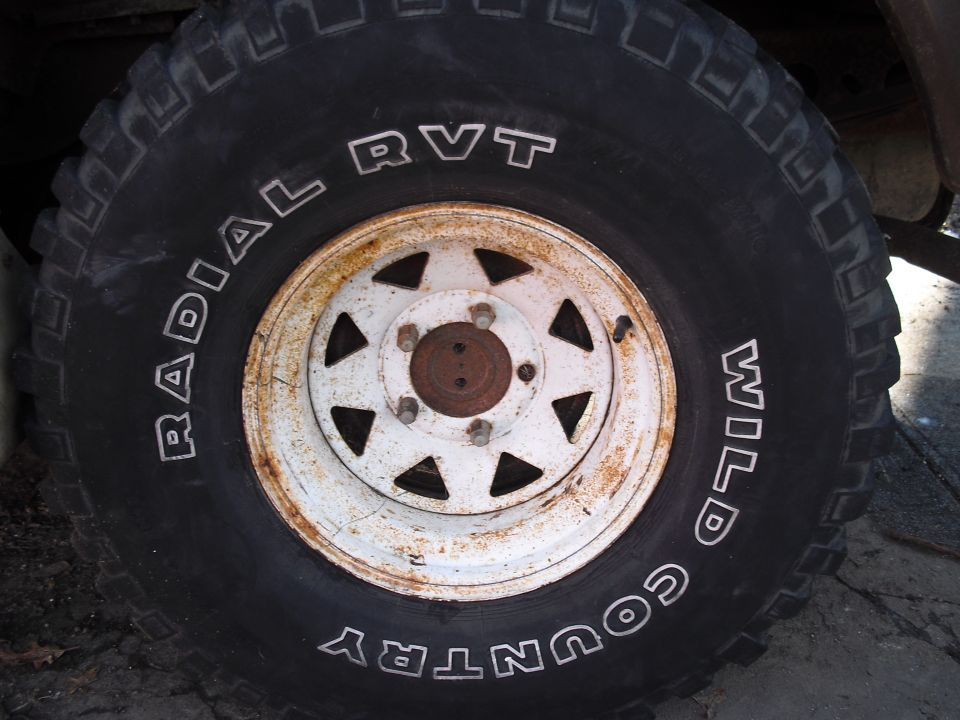 Close-up of a tire with 'RADIAL RVT WILD COUNTRY' text and a rusty white wheel