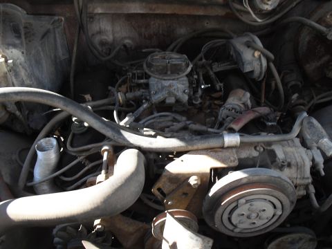 1986 Ford Bronco - Close-up view of an engine bay, focusing on the carburetor and associated components.